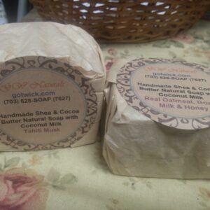 A pair of our handmade soaps wrapped in unbleached coffee filters with labels on a flowered tablecloth.