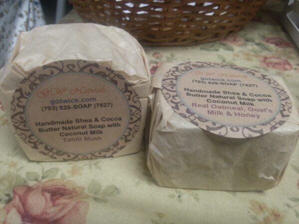 A pair of our handmade soaps wrapped in unbleached coffee filters with labels on a flowered tablecloth.